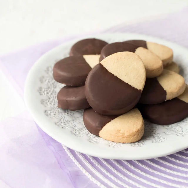 Plate of cookies with half chocolate and half plain on a white plate.