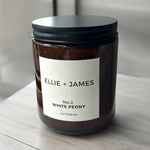Candle jar with 'Ellie + James' label on a wooden surface