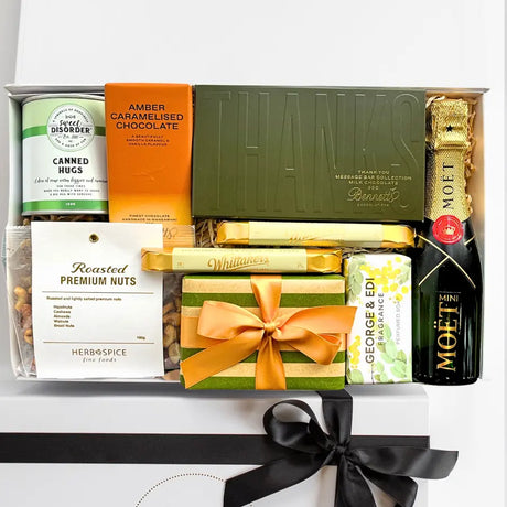 Gift basket with various items including chocolate, nuts, and a bottle of wine on a white background.