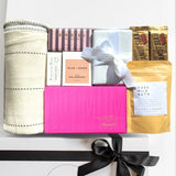 Gift set with various items including a towel, and bath products on a white background.