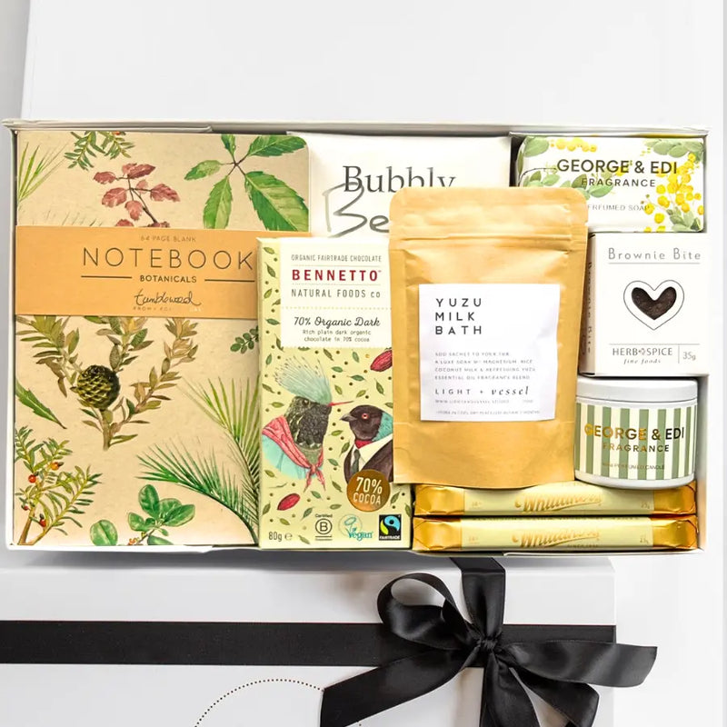 Gift set with products including a notebook, chocolate, and bath products on a white background.