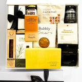 Gift basket with various items including chocolate, nuts, and a soap bar on a white surface.