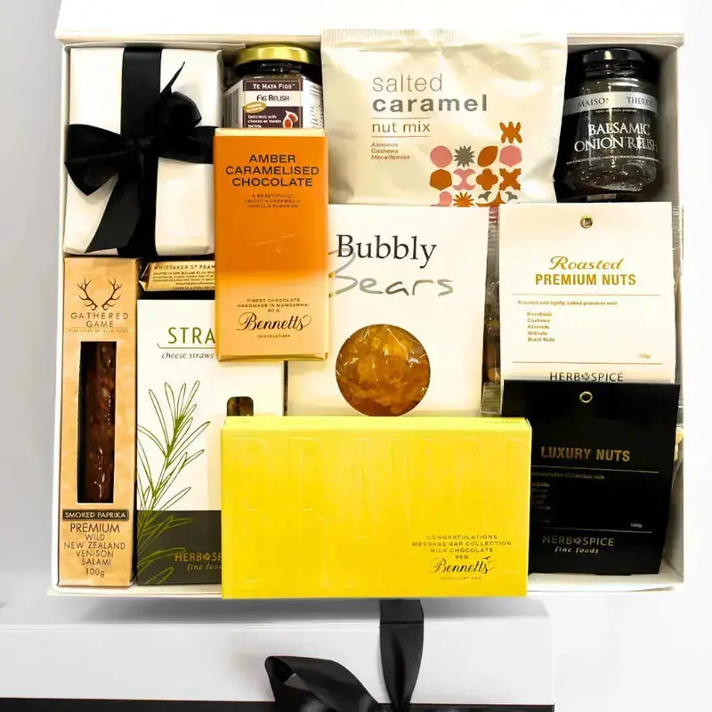Gift basket with various items including chocolate, nuts, and a soap bar on a white surface.