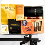 Gift box with assorted treats including biscuits, chocolate, and ginger fingers on a white background.