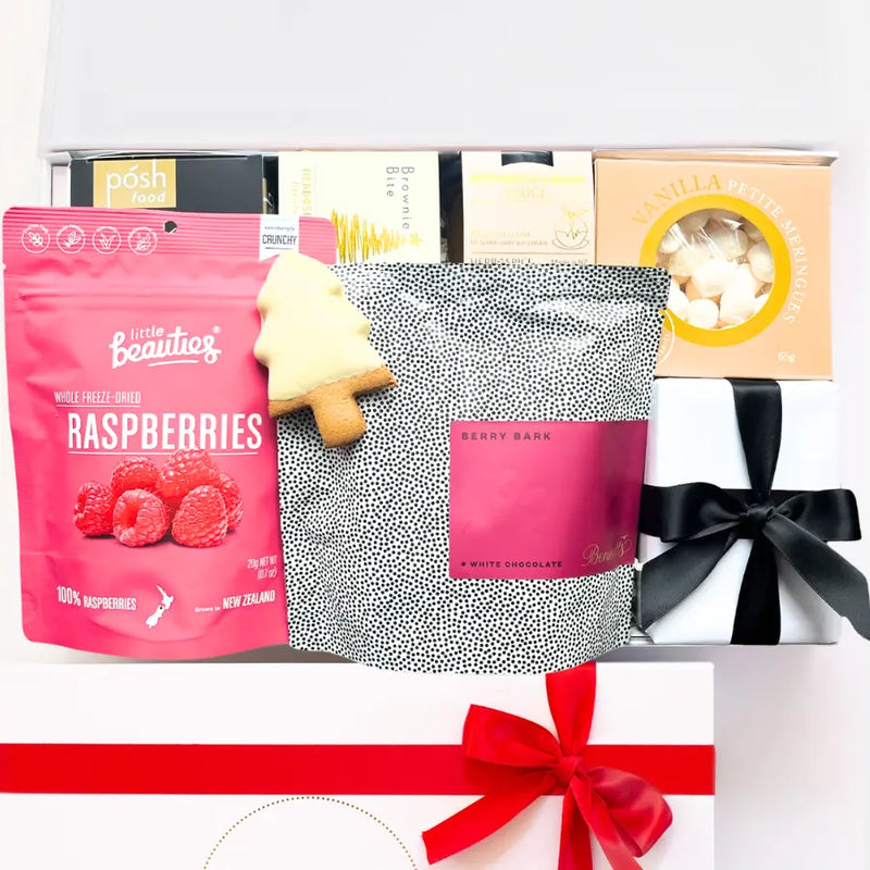 Gift box with assorted items including a pink bag of raspberries and a black and white patterned pouch.