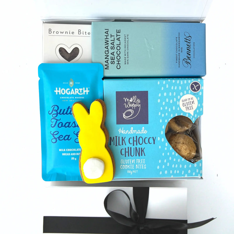 Assorted chocolate and cookie products with a yellow bunny-shaped tool on a white background