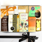 Assorted gourmet food and chocolate gift set with a black bow on a white background