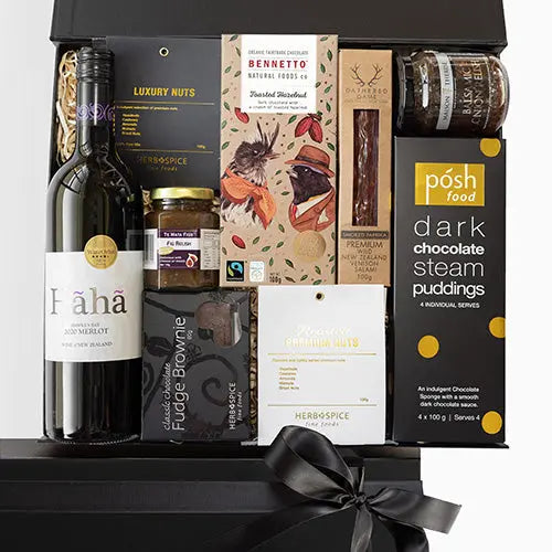 Gift basket with wine, chocolate, and other treats on a black background