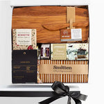 A luxury gourmet picnic gift box from Raine & Horne, featuring a wooden cheese board, a linen tea towel, a honey trio box, a luxury nut mix, fig relish, and organic chocolate.