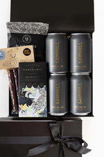 Gift set with Sawmill beer cans, chocolate bar, and other items in a black box.