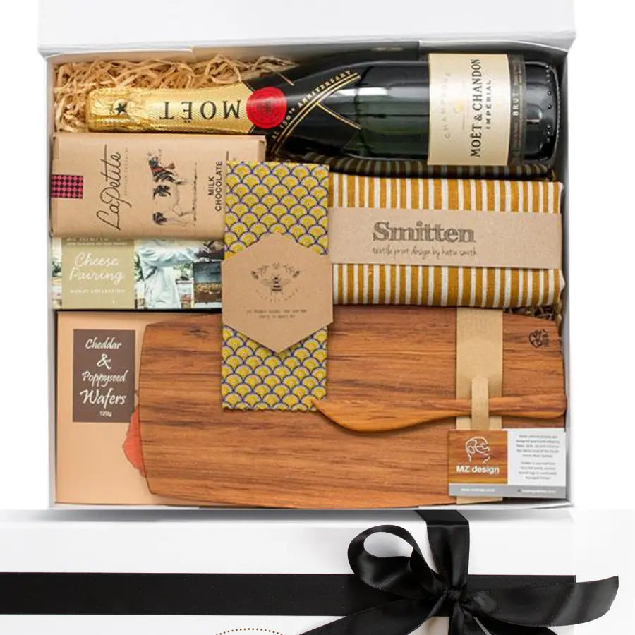 Gift basket with champagne, cheese, and wooden items on a white background
