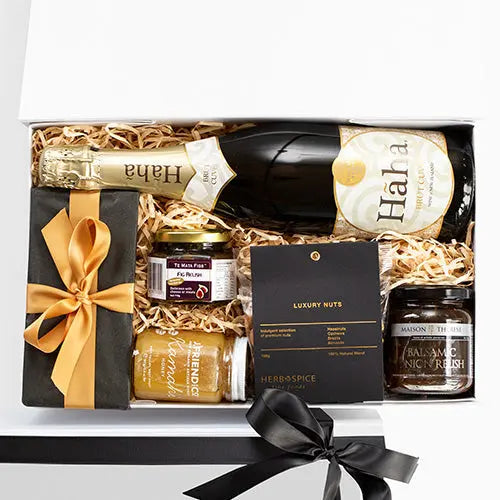Gift basket with Haha sparkling wine, nuts, and other items on a white background