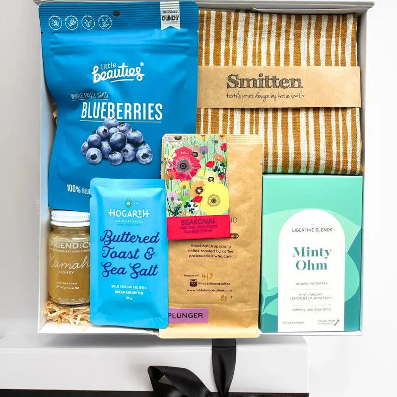 Assorted products including blueberries, buttered toast, sea salt, and a towel in a box.