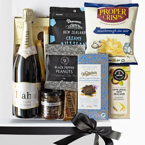 Gift basket with champagne, snacks, and other treats on a white background