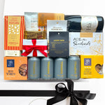 Gourmet gift basket with wine, snacks, and candies on a white background