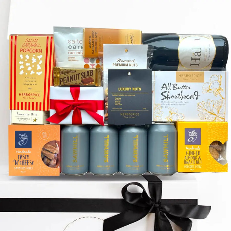 Gourmet gift basket with wine, snacks, and candies on a white background