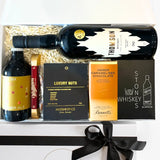A gift box containing a bottle of Thomson whiskey, a bottle of ginger ale, a set of whiskey stones, a luxury nut mix, a caramelized chocolate bar, and a keepsake gift box with tissue paper and a black ribbon.