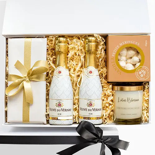 Gift set with Véuve du Vernay ice wine bottles, a candle, and a box of meringues.